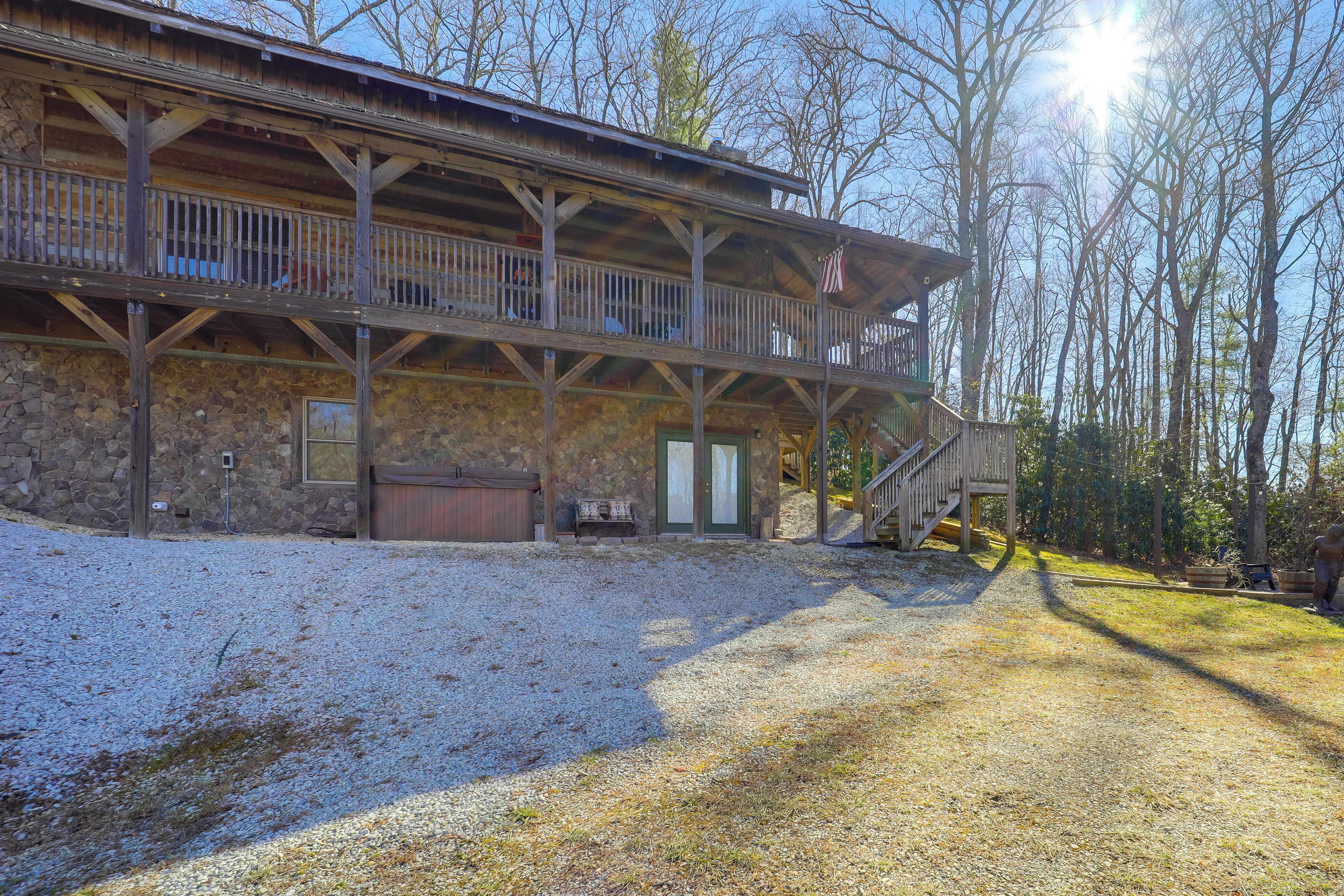 A rustic cabin with a stone foundation, wooden deck, and a covered porch.