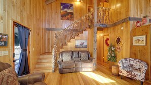 A wooden interior with a sofa, a patterned armchair, a staircase, and a Christmas wreath. - < 1 Mi to Linville Falls: Family Gem w/ Game Room! (Marion)