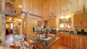 A wooden cabin interior with a central island, wooden benches, and a Christmas tree. - < 1 Mi to Linville Falls: Family Gem w/ Game Room! (Marion)