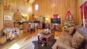 A cozy cabin interior with wooden walls, a dining area, a living room with a sofa, and a Christmas tree. - < 1 Mi to Linville Falls: Family Gem w/ Game Room! (Marion)