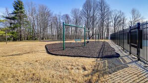 Un parque con un área de juegos, una banca y una valla.