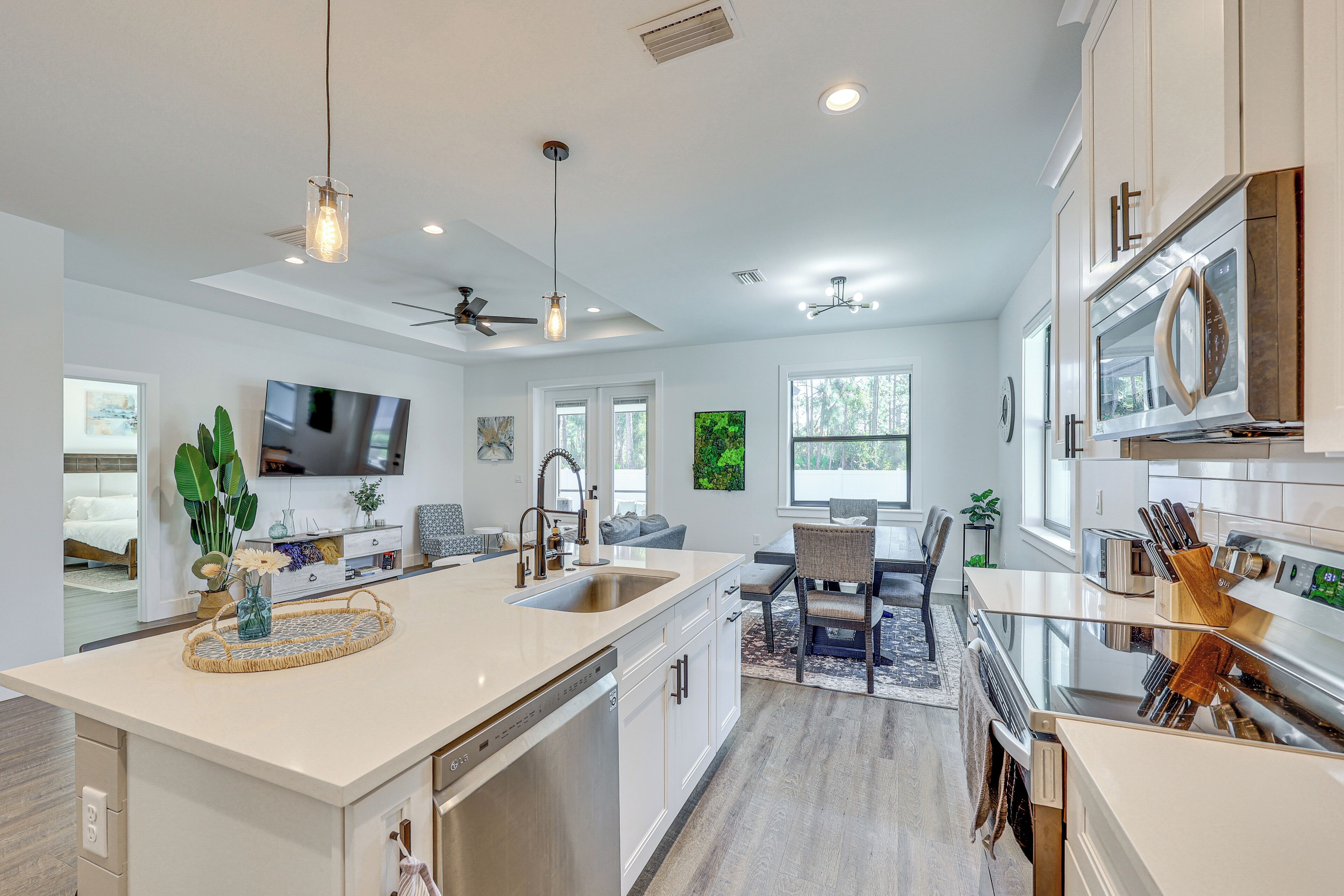 A modern kitchen with a large island, stainless steel appliances, and pendant lighting.