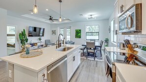A modern kitchen with a large island, stainless steel appliances, and pendant lighting. - Stone's Throw to All Major Attractions: Family Gem (North Port)