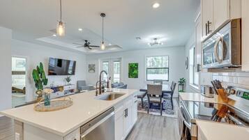 A modern kitchen with a large island, stainless steel appliances, and pendant lighting.