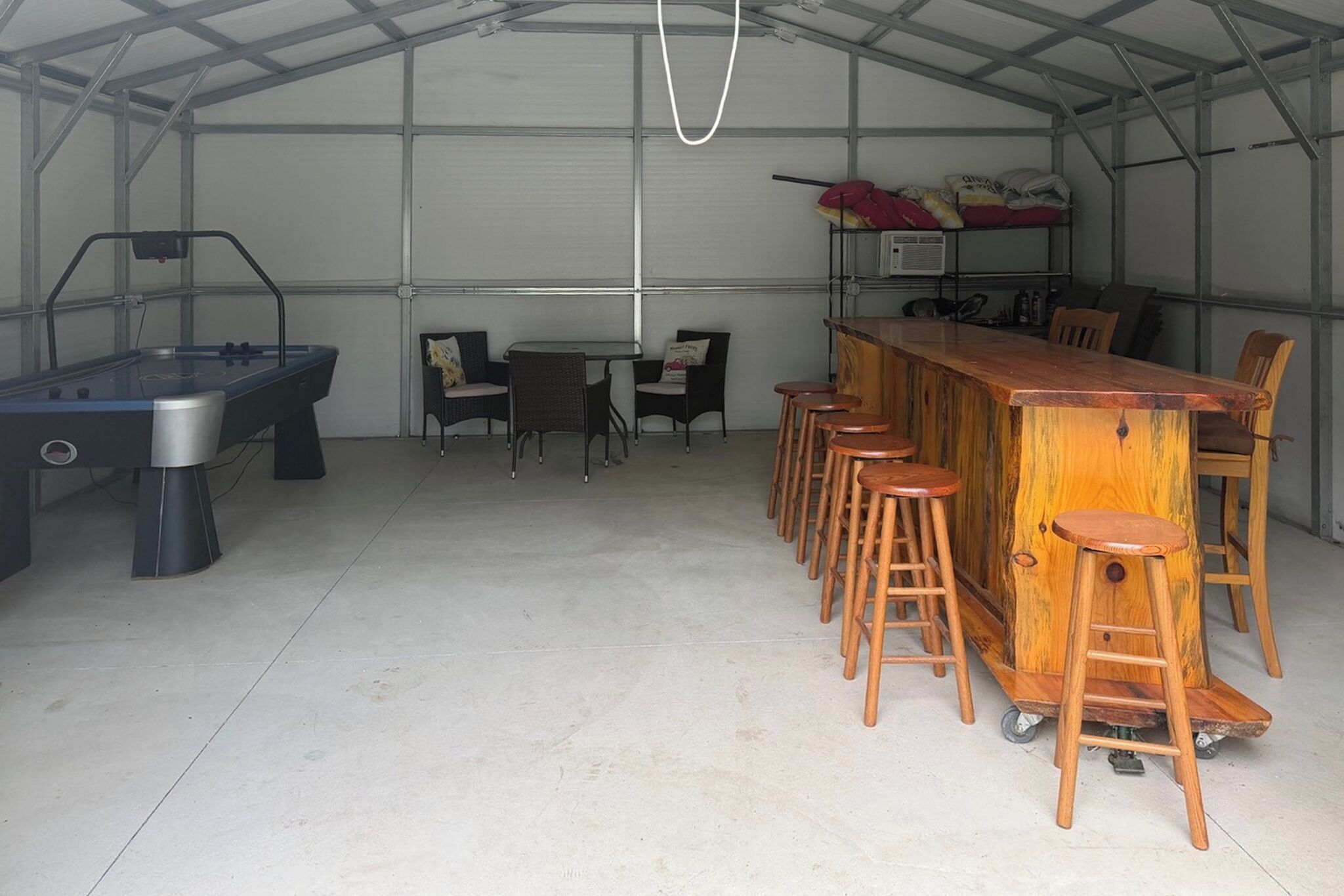 A bar area with stools and a pool table in a covered space.