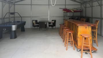 A bar area with stools and a pool table in a covered space.
