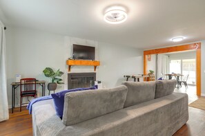 A living room with a sofa, a television, a fireplace, and a dining area in the background. - Lakefront Getaway w/ Dock & Views in Macon! (Macon)