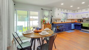A modern kitchen with white cabinets, a dining area with a round table, and a view to the outside. - Lakefront Getaway w/ Dock & Views in Macon! (Macon)