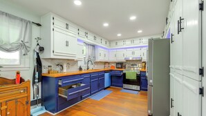 A modern kitchen with white cabinets, blue accents, and wooden flooring. - Lakefront Getaway w/ Dock & Views in Macon! (Macon)