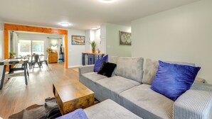 A spacious living room with a sofa, coffee table, and a dining area with chairs and a table. - Lakefront Getaway w/ Dock & Views in Macon! (Macon)