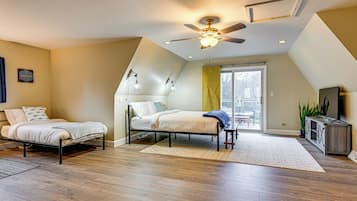 A bedroom with two single beds, a ceiling fan, a large window, and a TV stand.