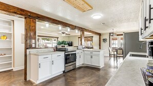 A spacious kitchen with white cabinets, a central island, and a dark wood floor. - Deck & Yard: Wolf Creek Waterfront Home in Grove! (Grove)