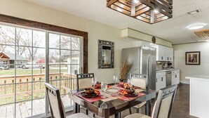 A dining area with a large window, a kitchen, and a view of the outside. - Deck & Yard: Wolf Creek Waterfront Home in Grove! (Grove)