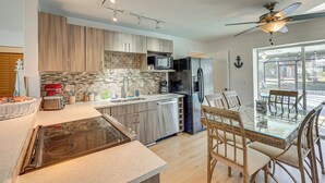 Une cuisine moderne avec des meubles en bois, une table à manger en verre et un ventilateur de plafond.