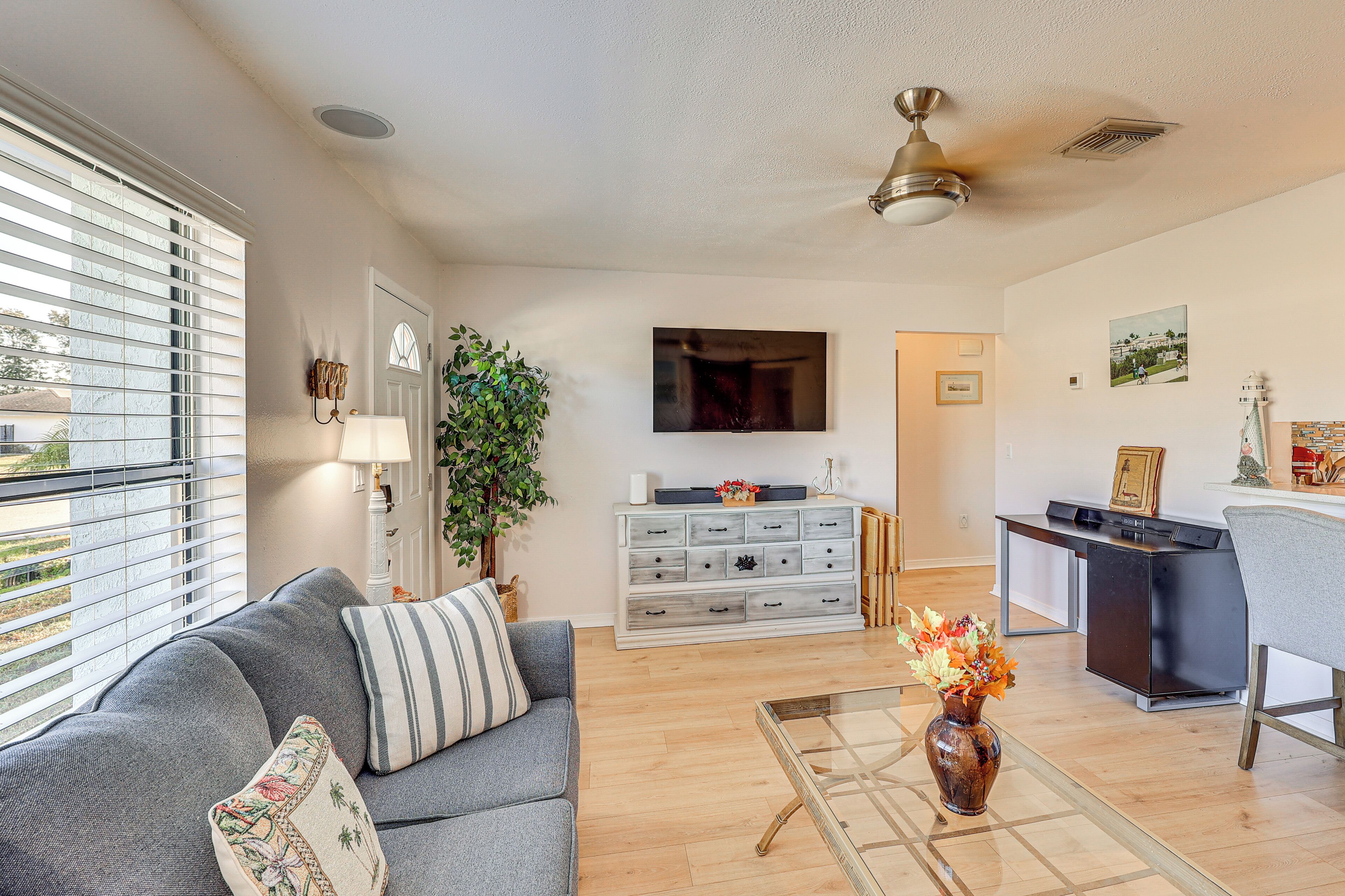 A living room with a sofa, a coffee table, a TV, a desk, and a plant.