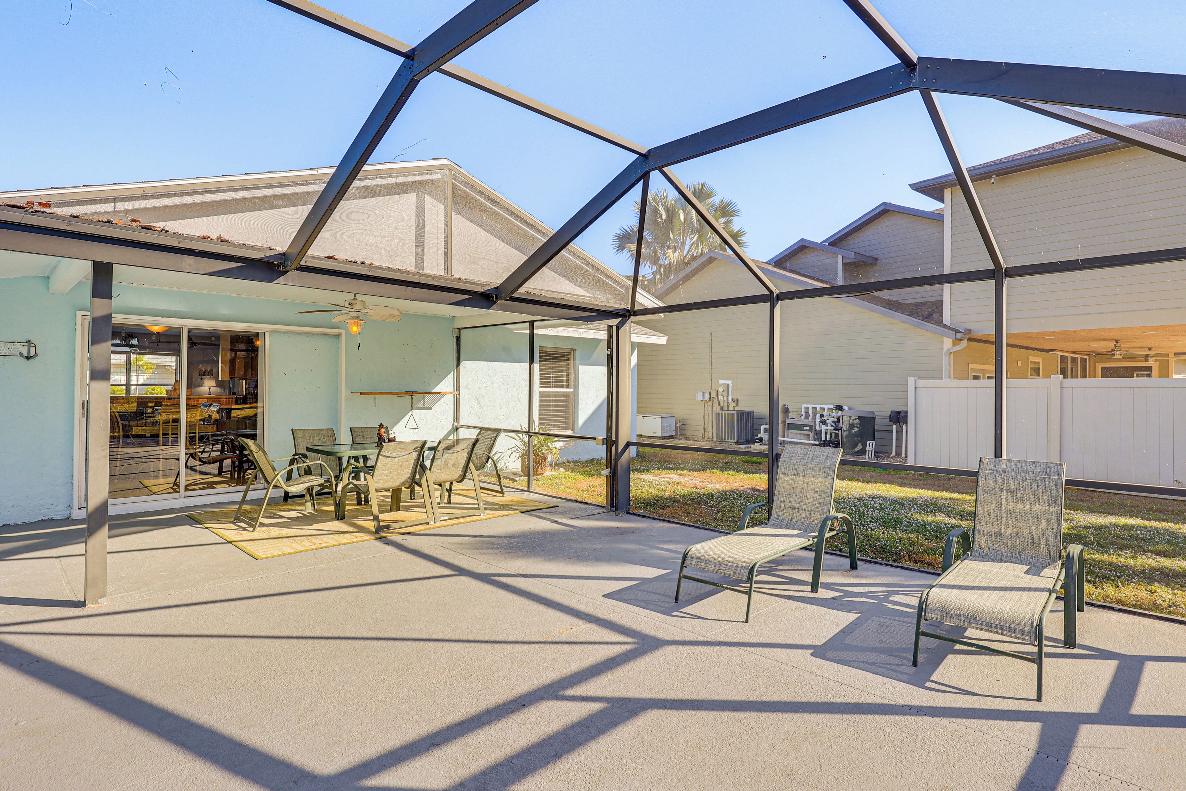 Eine Außenpatio mit Stühlen und Tisch, ein überdachter Bereich mit Decke sowie ein Gebäude im Hintergrund.