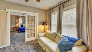 A living room with a beige sofa, a ceiling fan, and a window with curtains.