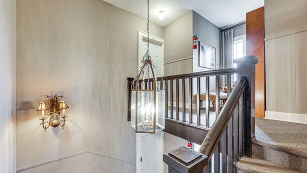 A staircase with a wooden handrail and a hanging lantern.