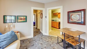 A hallway with a wooden bench, a framed map on the wall, and a door leading to a kitchen.