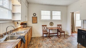 A kitchen with two sinks, a wooden dining table with chairs, and a clock on the wall. - < 1 Mi to Historic Dtwn Texarkana: Charming Home! (Texarkana)