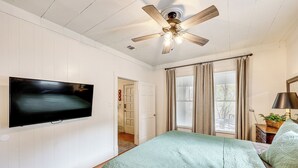 A bedroom with a bed, a ceiling fan, a TV, and a window with curtains. - < 1 Mi to Historic Dtwn Texarkana: Charming Home! (Texarkana)