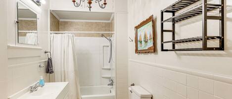 A bathroom with a sink, mirror, vanity, shower, and toilet.