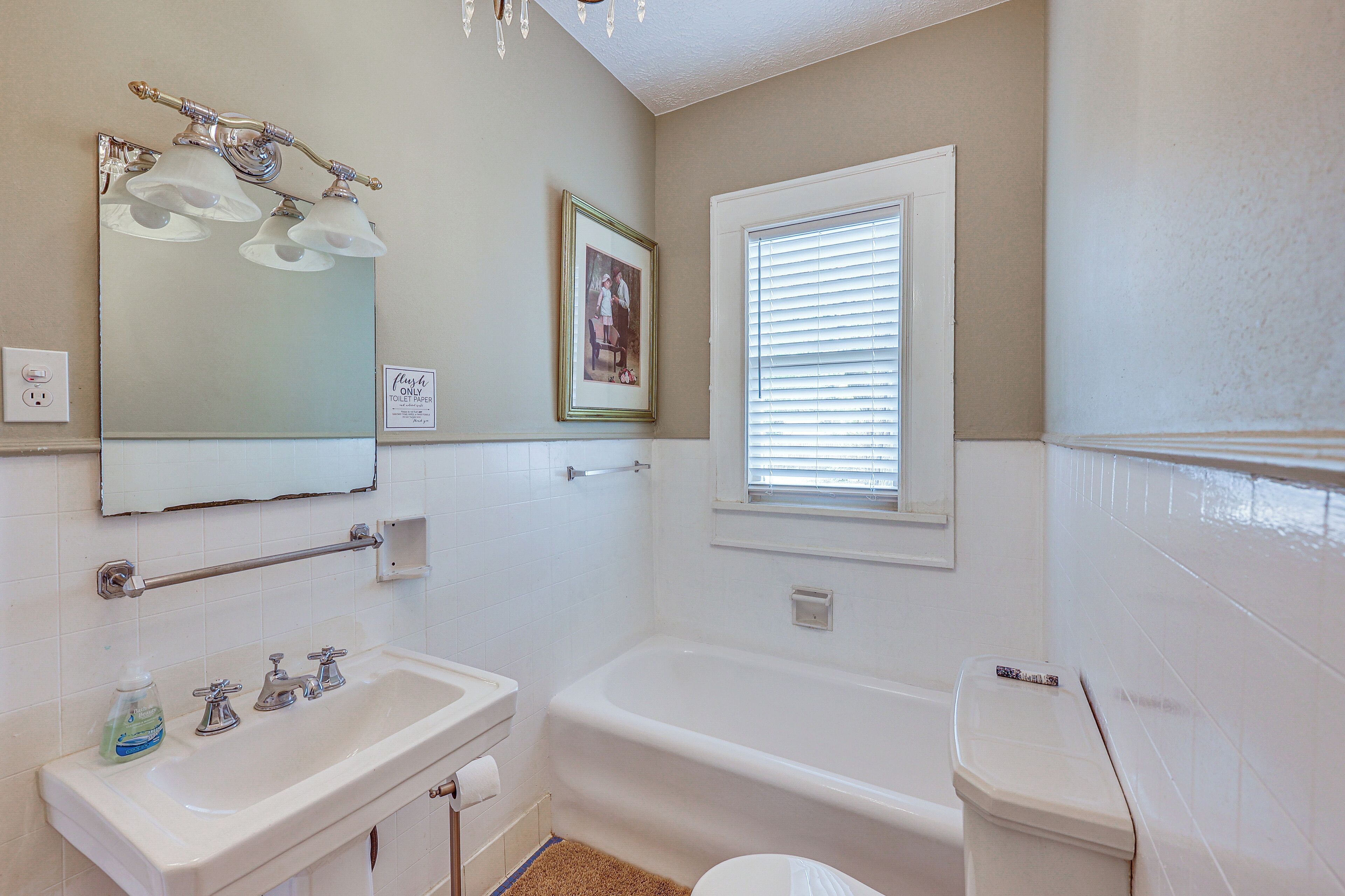 Une salle de bain avec un lavabo, un miroir et une baignoire.