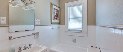 Une salle de bain avec un lavabo, un miroir et une baignoire.