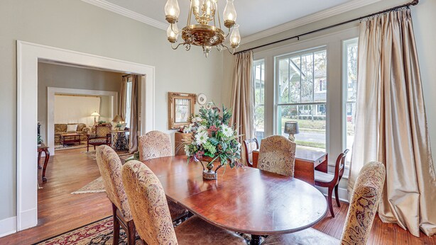 A dining room with a large wooden table, patterned chairs, a chandelier, and a view through large windows. - Great for Gatherings! Gem < 1 Mi to Dtwn Texarkana (Texarkana)