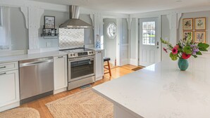 A modern kitchen with white cabinetry, stainless steel appliances, and a large island. - Escape to Cape Ann Steps to Beach & Pier! (Gloucester)
