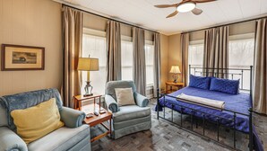 Une chambre d’hôtel avec un lit, une chaise, un canapé et un ventilateur de plafond.