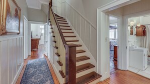 Una escalera de madera con barandilla, que conduce a una habitación con cama y cómoda.