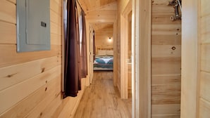 A wooden interior hallway with a bed at the end. - Lakefront Cabin Living w/ Dock Access on Sodus Bay (North Rose)