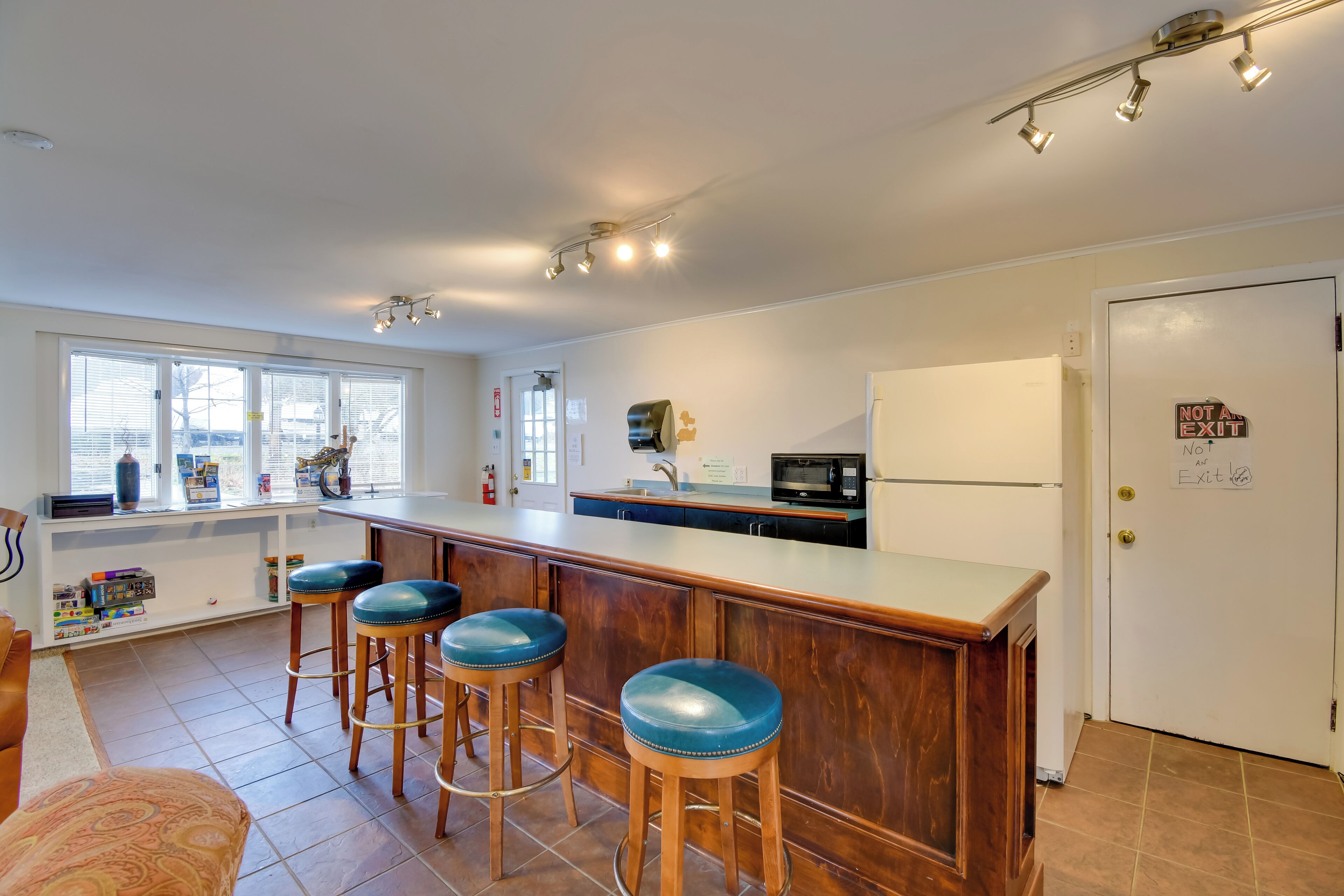 A modern kitchen with a bar area, white cabinets, and a microwave.