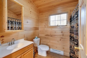 Een houten badkamer met een witte wastafel, toilet en raam.