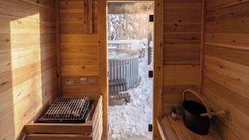 A wooden sauna room with a bench, a hot tub, and a bucket.