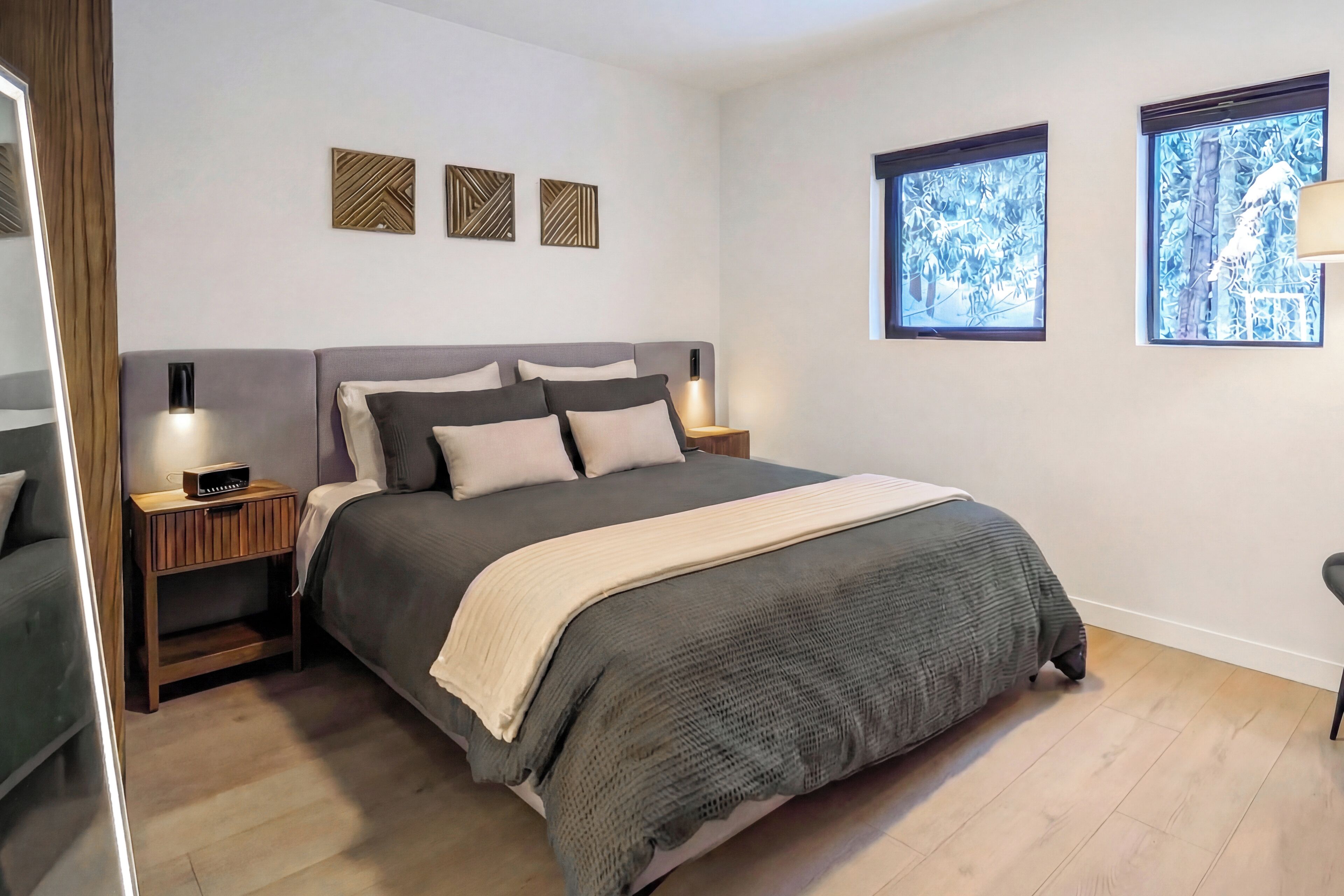 Ein modernes Schlafzimmer mit einem großen Bett, Nachttischen und dekorativer Wandgestaltung.
