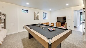 Een pooltafel in een kamer met een bed, een televisie en een raam.