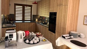 A modern kitchen with wooden cabinets, a built-in oven, a coffee machine, and a dining area with a table set for a meal. - Komfortowy Leśny Dworek (gmina Łopuszno)