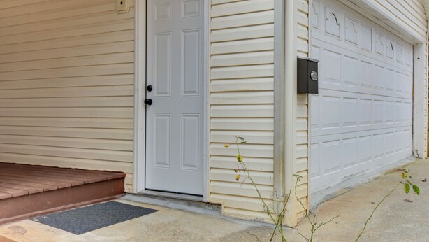 A house with a white front door, a garage door, and a small porch with a step.