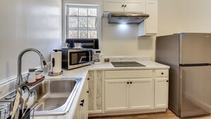 A modern kitchen with white cabinetry, stainless steel appliances, and a marble countertop.
