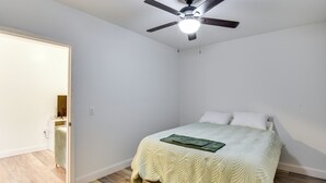 A bedroom with a bed, a ceiling fan, and a wooden floor.
