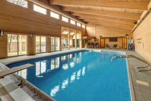 A large indoor swimming pool with wooden walls and ceiling, surrounded by lounge chairs and a small bar area. - Winter Long Lake Estate: Indoor Pool & Hot Tub (Long Lake)