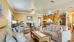 A spacious living room with a large sofa set, a wooden coffee table, and a dining area with chairs.