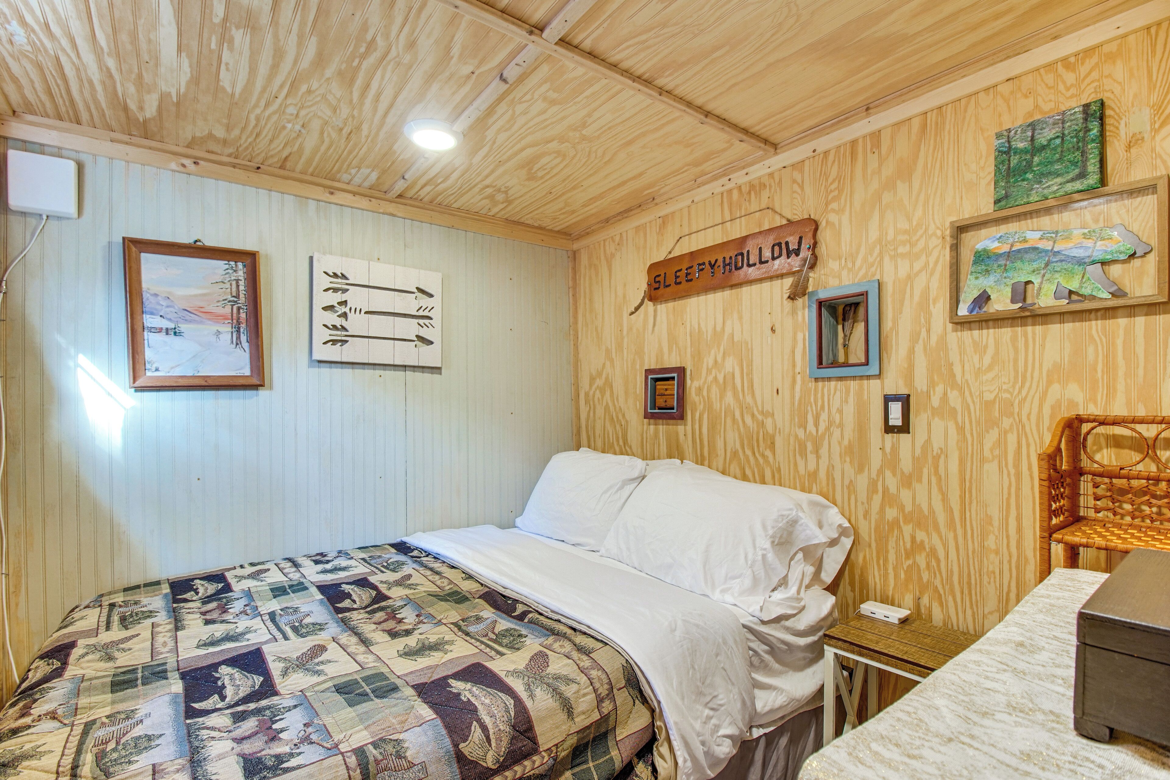 A wooden-paneled room with a bed, a small table, and a sign that reads "SLEEPY HOLLOW".