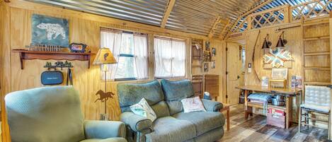 Een gezellig chaletinterieur met houten inrichting, een bank, een stoel en een eettafel.