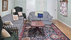 Ein Wohnzimmer mit zwei karierten Sofas, einem Holztisch, einem gemusterten Teppich und einer Wanddecke.
