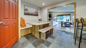 A modern kitchen with a wooden island, a dining area with a stone fireplace, and a large mirror reflecting the room. - NW Family Oasis: 6BR Modern Gem Near Rainier! (Puyallup)