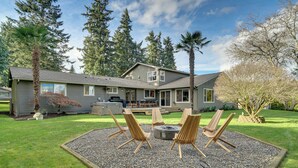 A house with a patio area featuring four wooden chairs and a fire pit. - NW Family Oasis: 6BR Modern Gem Near Rainier! (Puyallup)