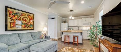 A modern kitchen with white cabinets, a bar area, and a ceiling fan.